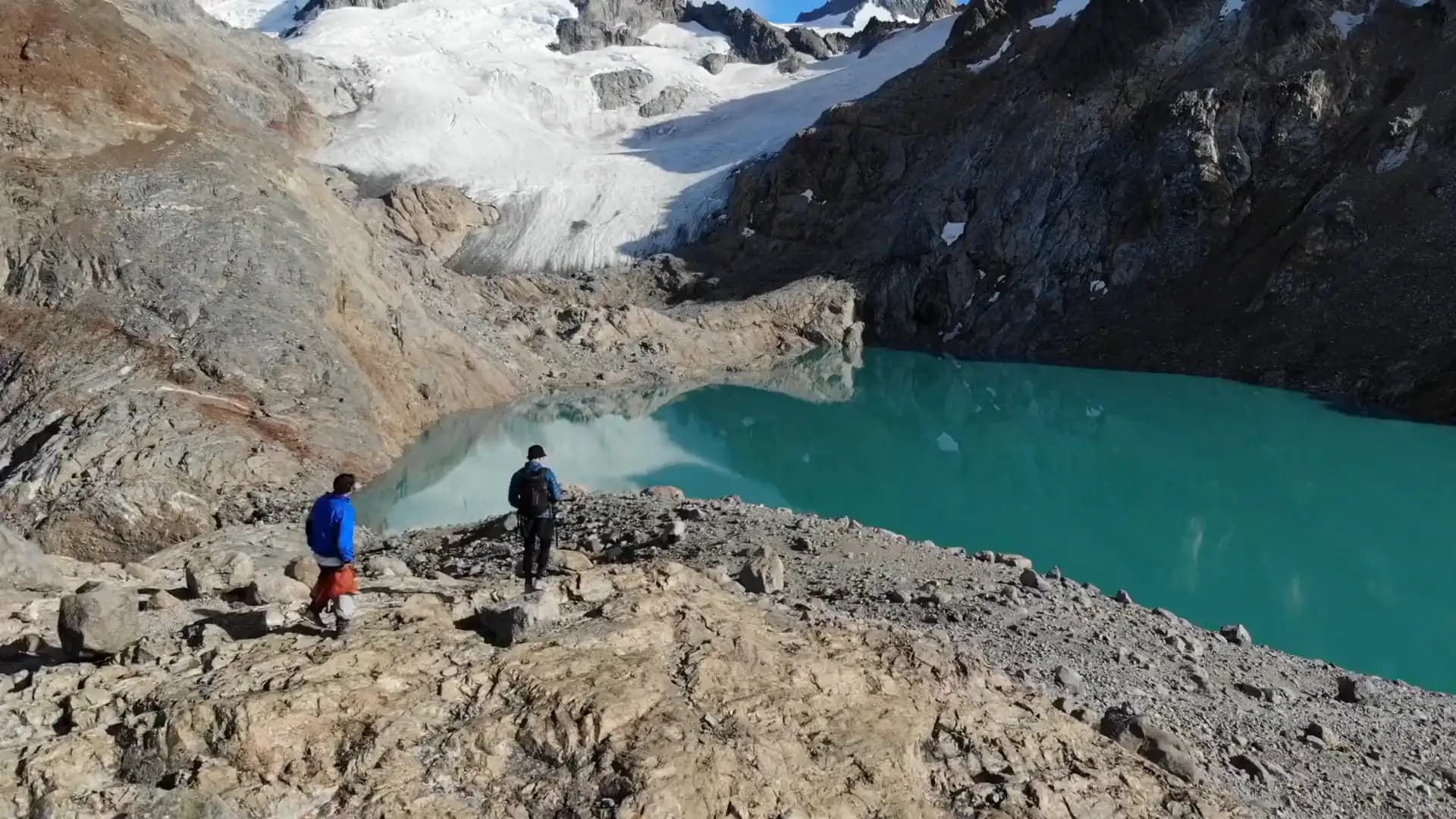 Laguna glaciar na Patagônia chilena, com dois viajantes na margem